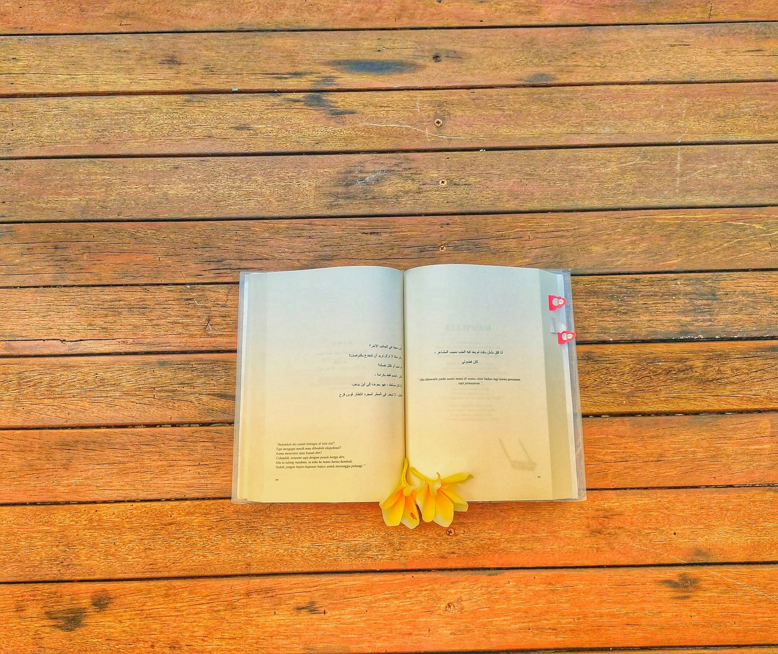 an open book on a wooden table with a flower